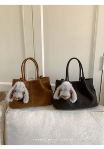 Detail of faux suede tote bags in caramel and dark brown colors with plush bunny charms