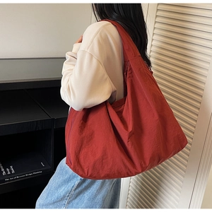 Detail of red oversized nylon tote bag showing its soft texture and large capacity on shoulder