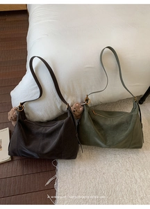 Détail du sac hobo vintage avec pendentif ours en peluche sur une literie blanche