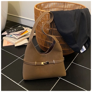 Detail of dark brown leather tote featuring elegant gold buckle and vintage texture