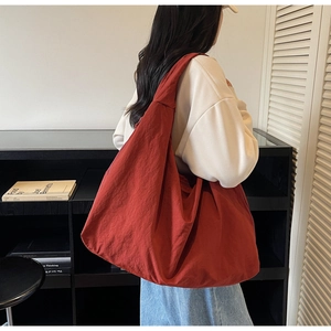 Detail of red nylon tote bag featuring durable pleated texture and large capacity