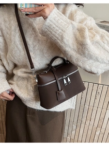 Detail view of brown matte leather crossbody box bag with silver hardware and dual zippers