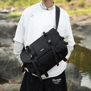 Detail of durable black nylon messenger bag with technical straps and brand logo