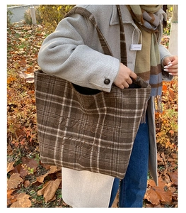 Close-up of vintage brown plaid tote bag with Happy Baby embroidery in autumn forest