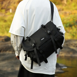 Outdoor shot of the large black nylon messenger bag with buckle closure and logo detail
