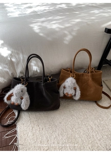Detail of minimalist suede tote bags in grey and tan with plush rabbit charms