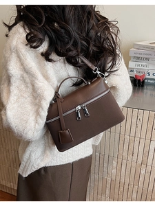 Detailed side view of large brown leather crossbody bag with dual metal zippers and strap