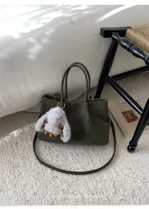Detail of olive green tote bag with textured leather and a plush rabbit charm