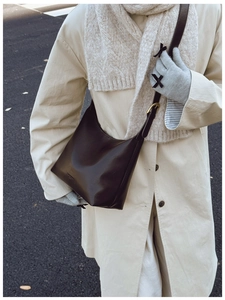 Detail of adjustable leather strap with gold buckle on a dark brown tote bag