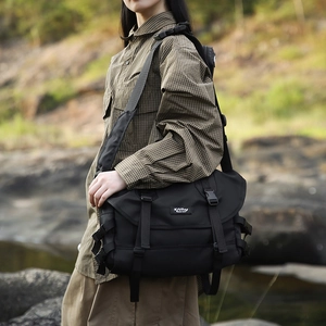 Detailed outdoor view of a black high-capacity messenger bag with nylon texture and buckle