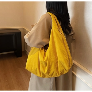 Close-up of bright yellow large tote bag with wrinkled texture worn over the shoulder