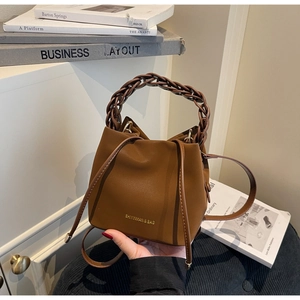 Detail of dark brown bucket bag with braided ring handle and gold brand lettering