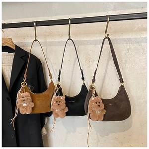 Close-up of vintage suede crescent bags in three colors with plush bear charms