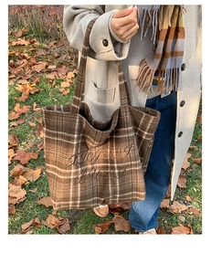 Detail of vintage plaid tote bag with brown embroidery on textured wool fabric