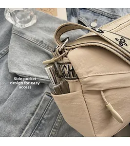 Detail view of beige nylon crossbody bag featuring side pocket for storage and logo strap