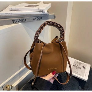 Brown leather bucket bag with woven handle and gold lettering on white background