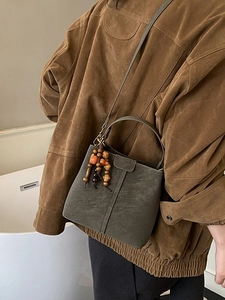 Vintage green leather bucket bag with wooden bead charm and long shoulder strap