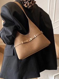 Brown retro hobo tote bag with gold buckle on a model wearing a black blazer