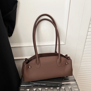 Detailed view of brown litchi pattern leather baguette bag with silver rivet hardware