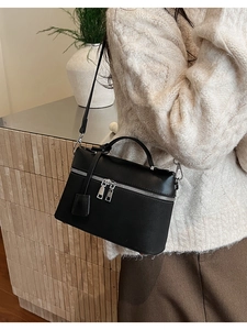 Detailed side view of black luxury texture crossbody bag worn by a model in soft lighting