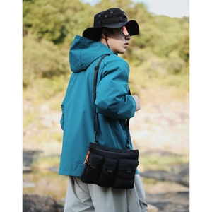 Sac bandoulière outdoor avec zips orange sur veste bleue dans un décor naturel