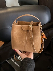 Vintage brown leather bucket bag with top handle, wood bead tassel and adjustable strap