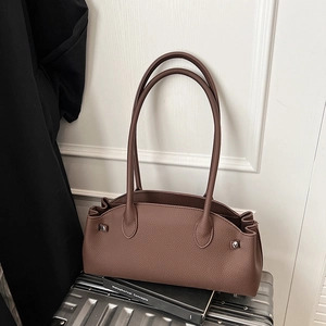 Detail of dark brown lychee leather baguette bag with silver buckles and pleated sides
