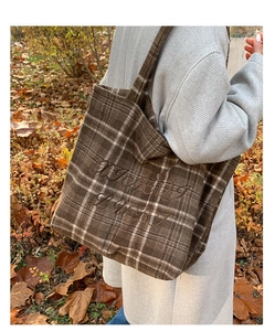 Detail of a large brown plaid wool tote bag with floral letter embroidery for winter