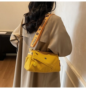 Detail of a bright yellow nylon crossbody bag with wide floral lettered shoulder strap