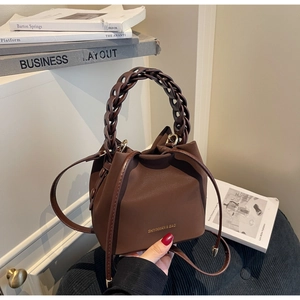 Detailed shot of dark brown leather bucket bag with woven handle and drawstring closure