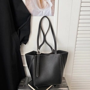 Detail view of black lychee grain leather tote bag with white stitching and triangle buckle