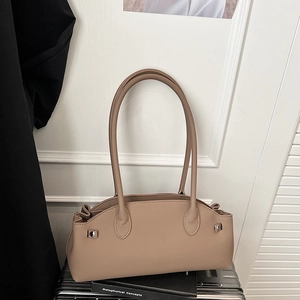 Detailed view of lychee grain leather shoulder bag with silver studs on a silver suitcase