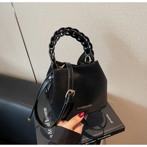 Detail of matte black leather bucket bag with woven handle and gold hardware