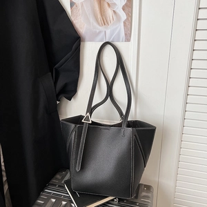 Detail of black leather tote bag featuring contrast white stitching and triangle metal buckle