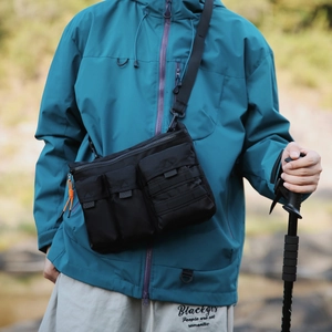 Détail du sac de messager tactique noir avec poches fonctionnelles et cordons orange
