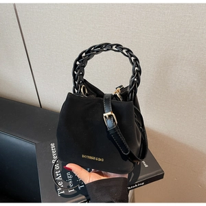 Detail of black matte bucket bag with woven chain handle and gold brand lettering
