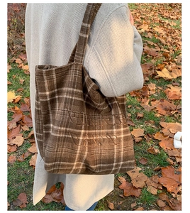 Detailed embroidery on vintage plaid tote bag with Flower Girl script in outdoor setting