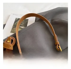Detail view of brown leather bag showing comfort handle, fur ball and gold hardware
