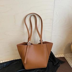 Macro detail of brown pebbled leather tote bag featuring a silver triangle metal buckle