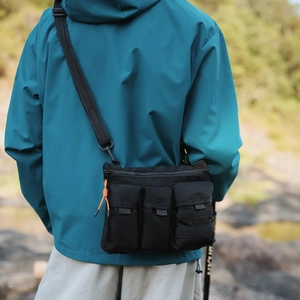 Détail du sac bandoulière tactique noir avec poches multiples et tirette orange vive