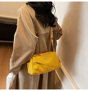 Detail view of bright yellow multi-zipper crossbody bag with branded wide textile strap