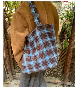 Outdoor view of a vintage plaid tote bag with blue and brown checkered embroidery