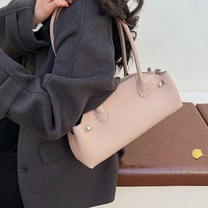 Detailed close-up of a nude leather baguette bag with silver hardware on a winter coat