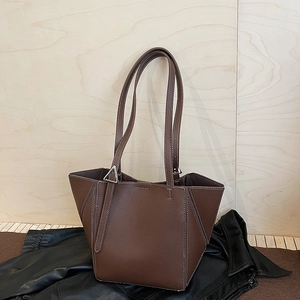 Detailed close-up of dark brown leather tote bag with white contrast stitching and hardware