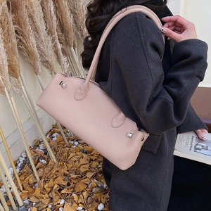Close-up of pink lychee grain leather shoulder bag with metallic details in autumn setting