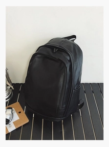 Detail of waterproof black leather backpack with side pockets on a dark wooden table