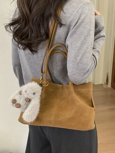 Minimalist brown suede shoulder bag with plush rabbit charm shown on model back