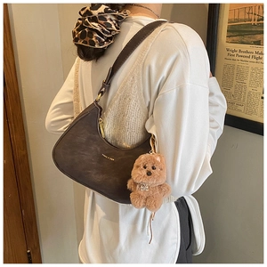 Detail of vintage brown leather crescent bag with gold branding and plush dog charm