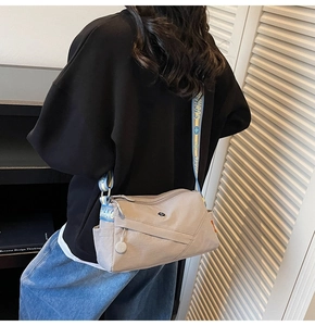 Detail of grey crossbody bag featuring a blue and yellow printed wide shoulder strap