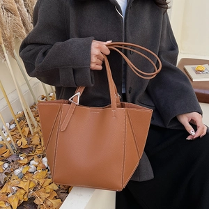 Detail of warm brown leather tote bag with geometric stitching and metal buckle side
